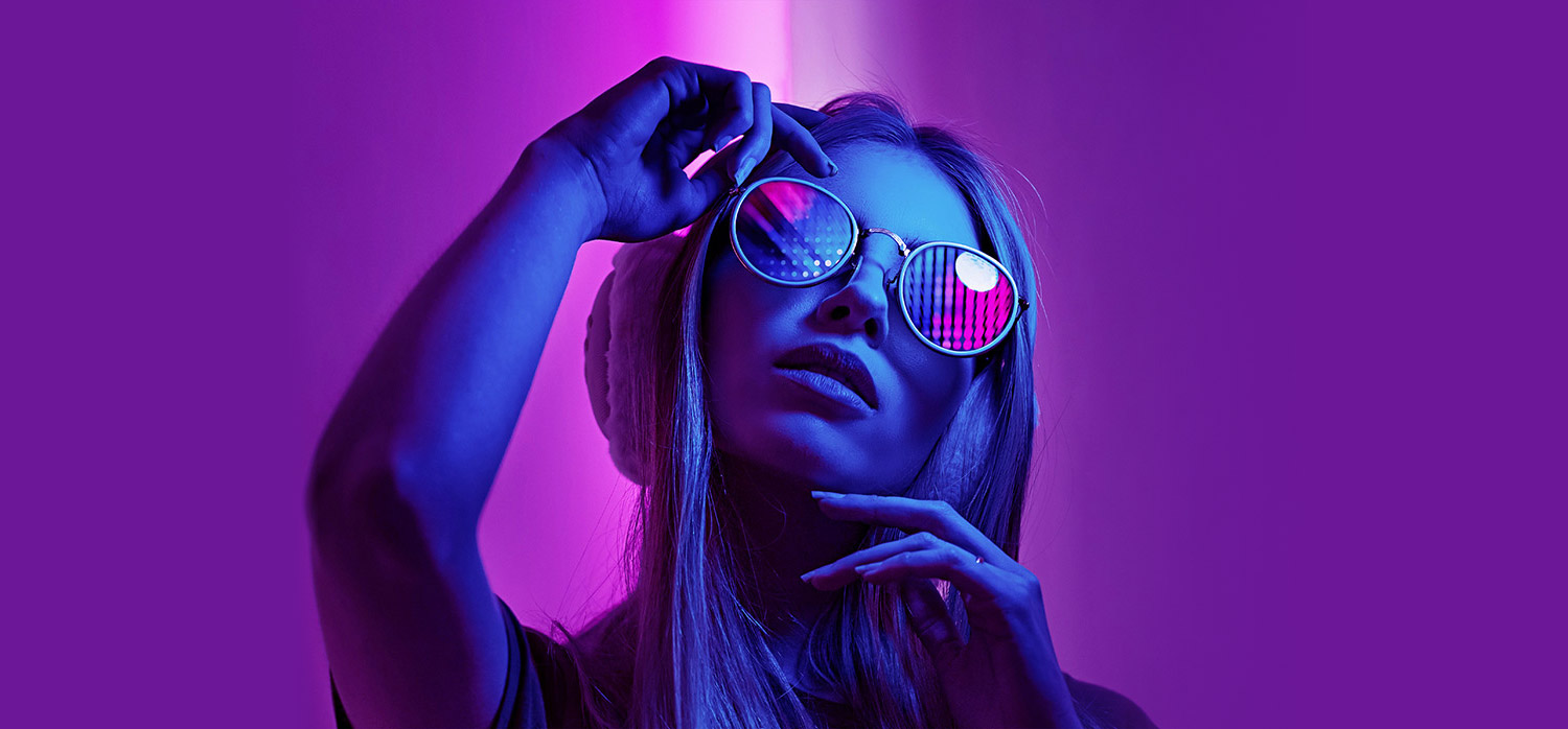 DJ facing a crowd at his deck. Photo with a purple hue